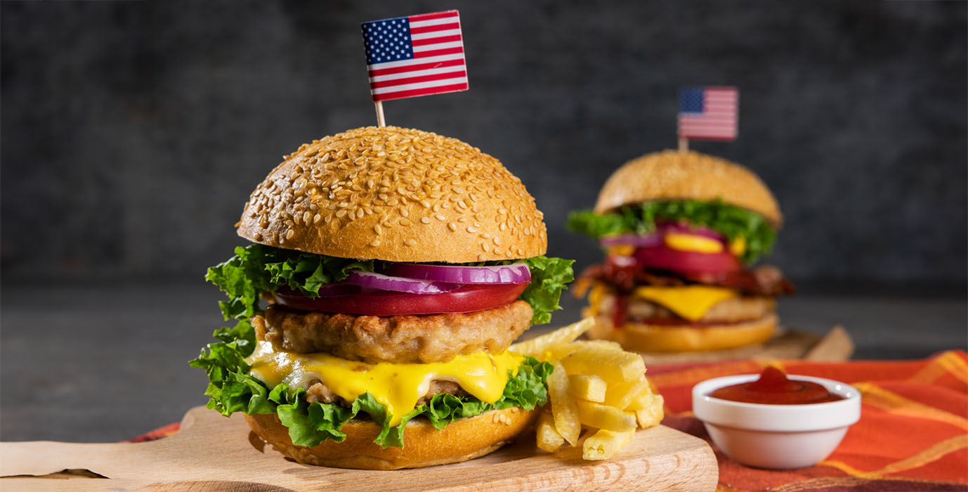 Foto de dois hamburgers grandes com bandeiras pequenas dos EUA no topo